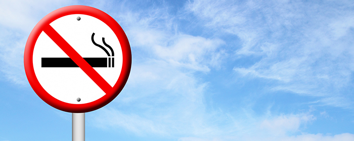 Rökning förbjuden-skylt mot blå himmel