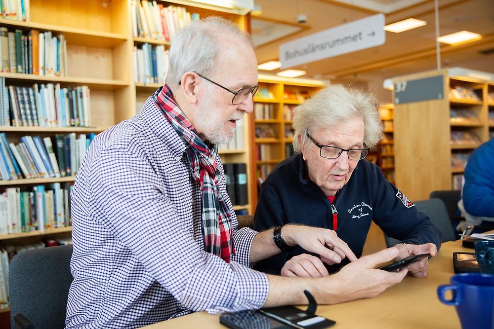 Dekorationsbild Två äldre herrar tittar gemensamt och pratar om en mobil